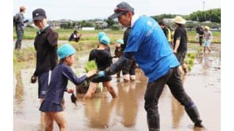 指導する水稲農家と田植えを楽しむ児童