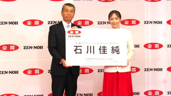 野口栄代表理事理事長（左）から巨大名刺を受け取る石川佳純さん
