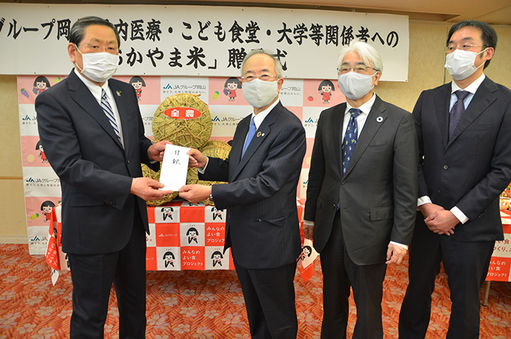 青江会長（左）から目録を受け取る関係組織の代表者