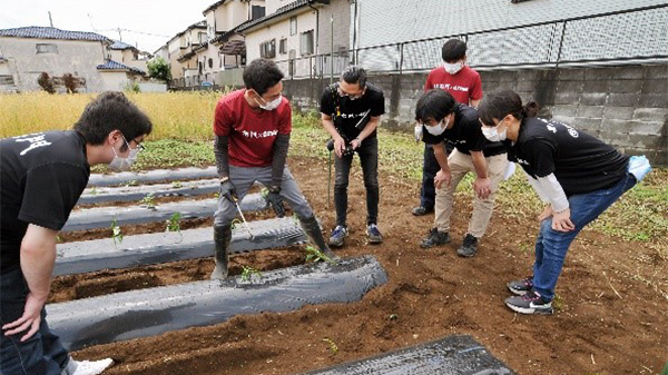 サツマイモ植え付けを指導。黒Tシャツのスタッフが右門、赤Tシャツが＠FARM